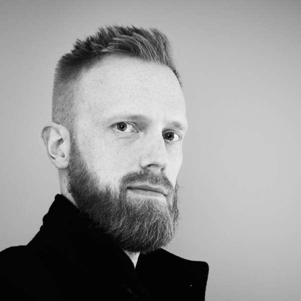 Headshot of me with medium long beard, dressed in a black coat